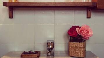 Un baño con un lavamanos blanco, un estante de madera encima y un espejo.
