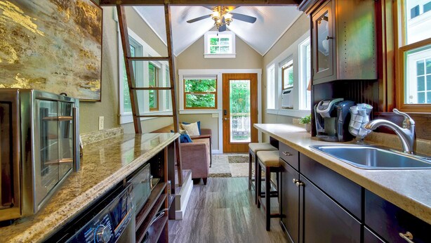 A kitchen with a ceiling fan, a large window, and a door leading outside. -  Tiny House Bungalow (Reynoldsburg)