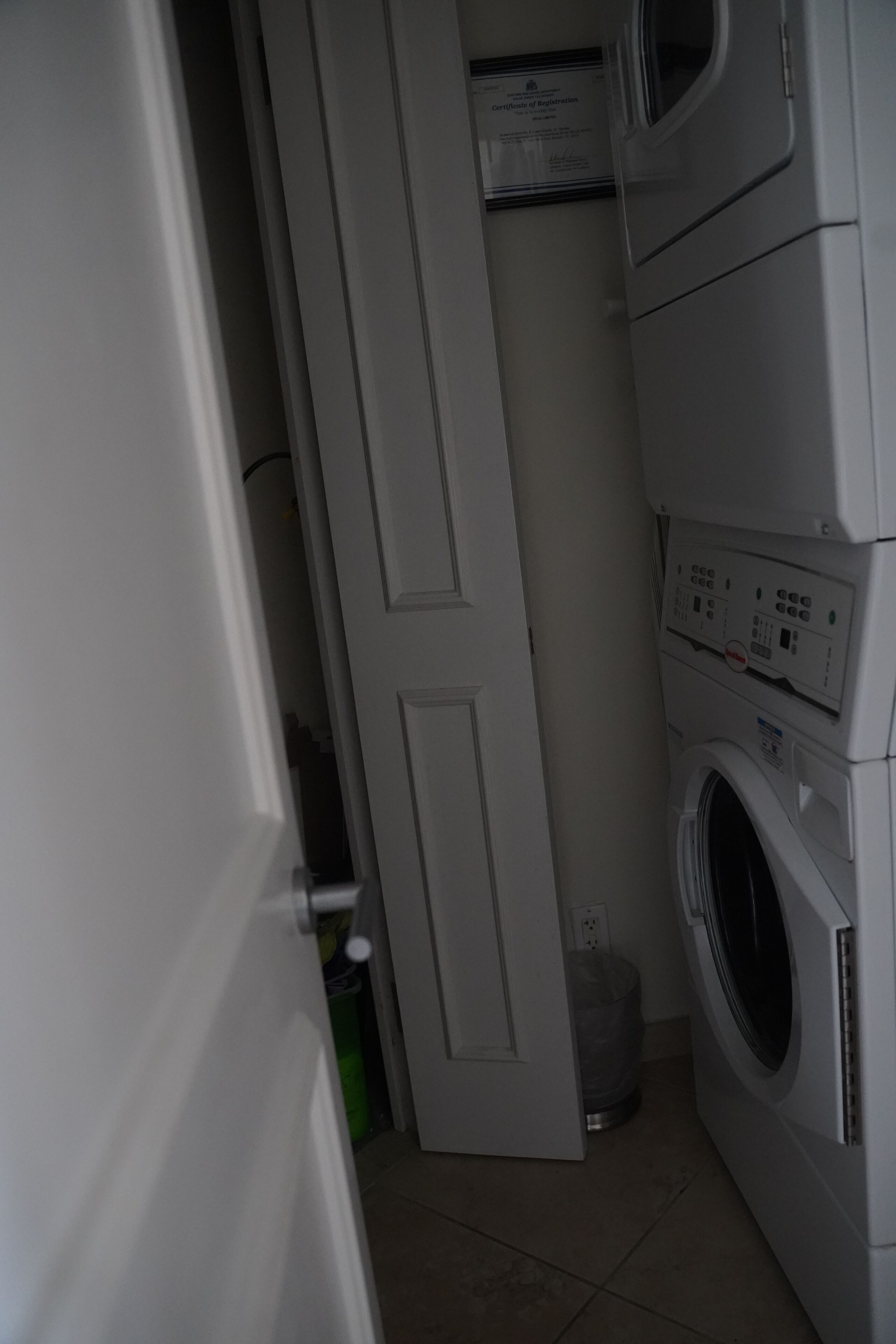 Een wasserette met gestapelde wasmachines, een deur en een prullenbak.