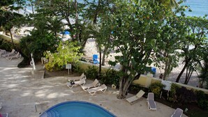 A swimming pool with lounge chairs and a view of the beach.