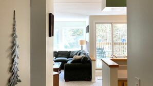 A narrow hallway leading to a living room with a dark-colored sofa and a small table. - Year Round Green Mountain Escape - Ski - Swim - Tennis - Hike - Golf (Warren)