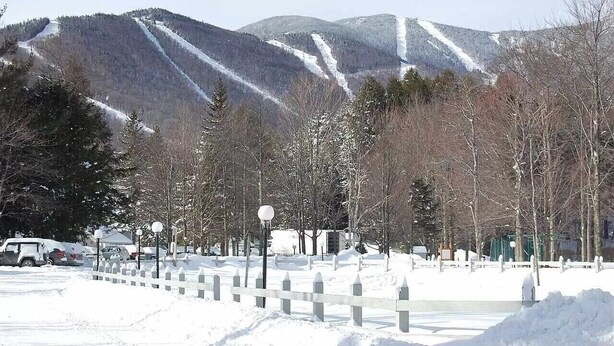 A snowy landscape with a mountain in the background, a white fence, and bare trees. - Year Round Green Mountain Escape - Ski - Swim - Tennis - Hike - Golf (Warren)