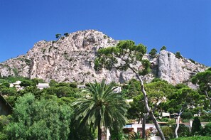 A rocky mountain with sparse vegetation and a few houses at its base. - 1BR CannesVacationRental by AmericanVacationLiving (Cannes)