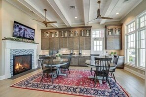A modern kitchen with a fireplace, dining area, and large windows.