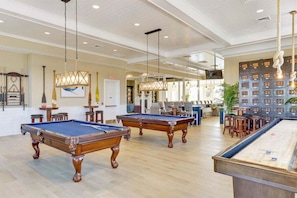 A pool table area with multiple pool tables, a bar area, and a seating area with chairs and tables.