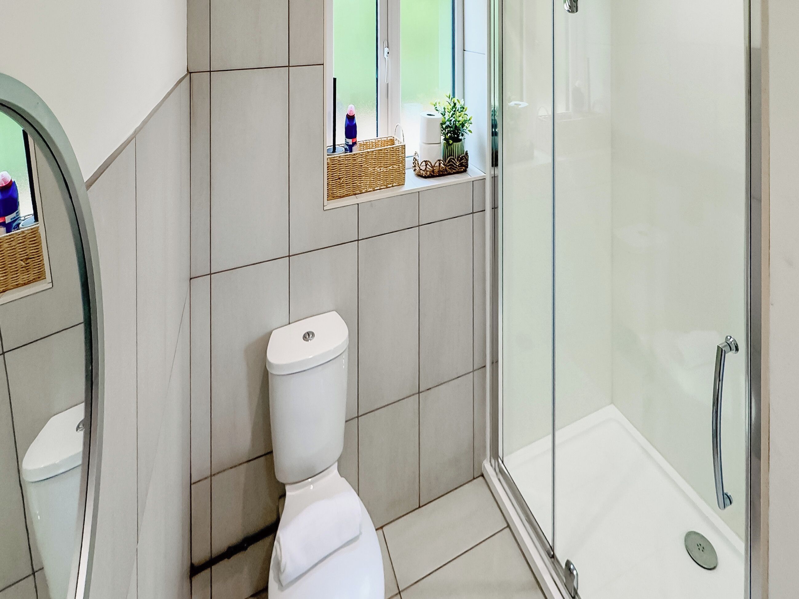 Un bagno moderno con il water, una cabina doccia in vetro e una piccola finestra con vista.