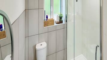 Un bagno moderno con il water, una cabina doccia in vetro e una piccola finestra con vista.