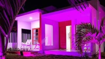 Una casa moderna con techo plano, ventanas amplias y una puerta roja.