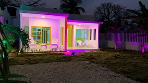 A modern house with a bright exterior, a porch with chairs, and a gravel driveway. - Bahia Tropical Coveñas (San Antero)