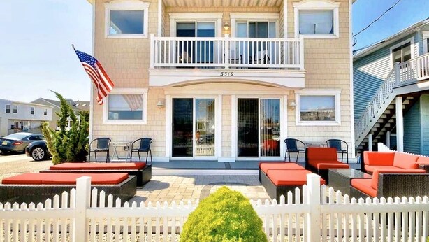 Un bâtiment à deux étages doté d’un balcon, d’un drapeau et d’un espace extérieur aménagé pour s’asseoir.