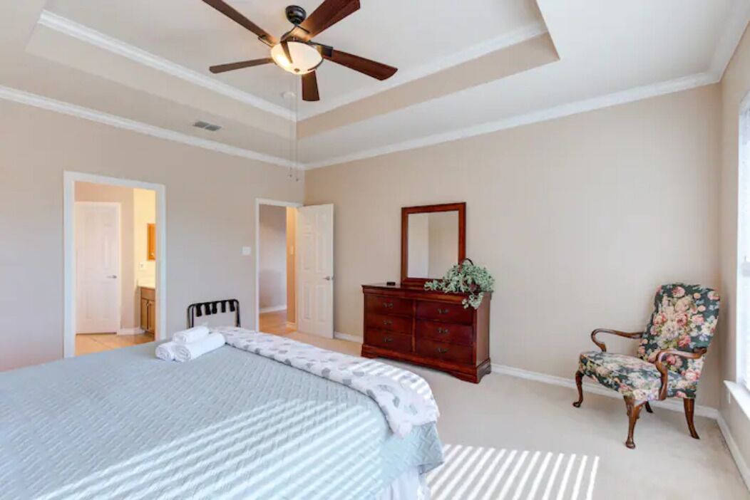 Un dormitorio con cama, cómoda, silla, ventilador de techo y espejo.