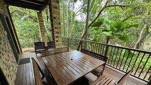 A wooden deck with a table and benches, surrounded by a railing and lush greenery. - Avalon in Arcadia Magnetic Island (Arcadia)
