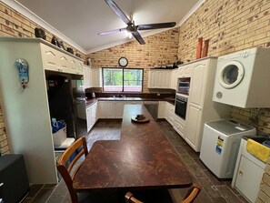 A kitchen with a central island, white cabinets, a built-in oven, a washing machine, and a ceiling fan.