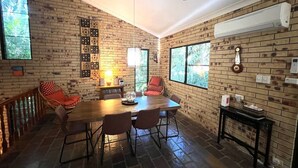 A dining area with a brick wall, a ceiling fan, and a table with chairs. - Avalon in Arcadia Magnetic Island (Arcadia)