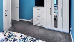 Een slaapkamer met een bed, een dressoir, een televisie en een kledingkast.