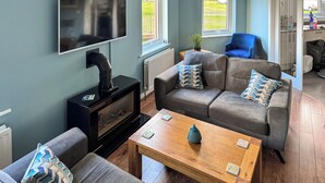 Een woonkamer met een bank, een salontafel, een televisie en een open haard.