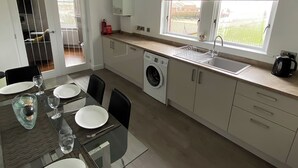 Een moderne keuken met een ingebouwde wasmachine, een spoelbak en een raam met een decoratieve gordijnboog.