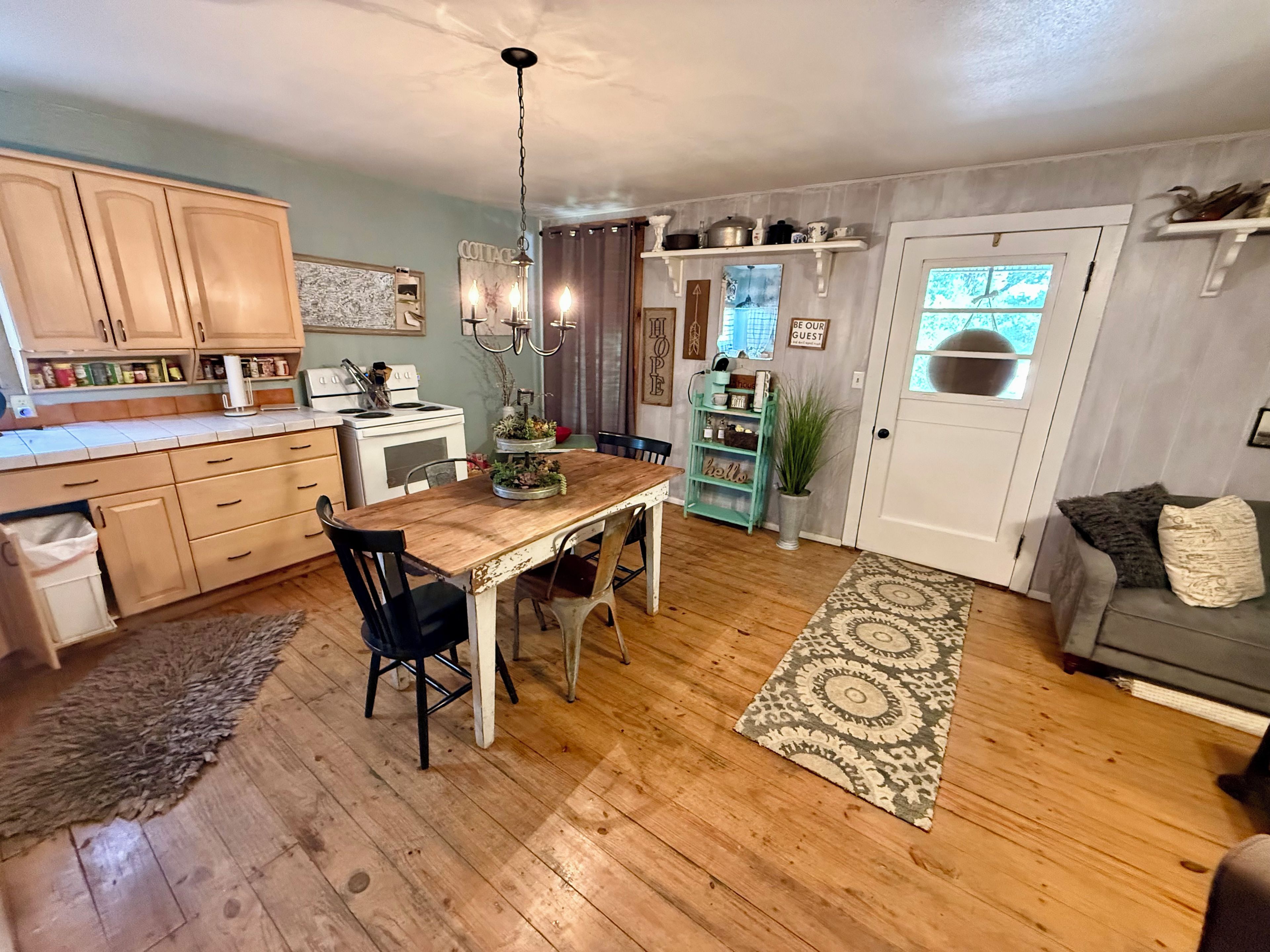 A cozy kitchen with wooden cabinets, a dining table, and a chandelier.