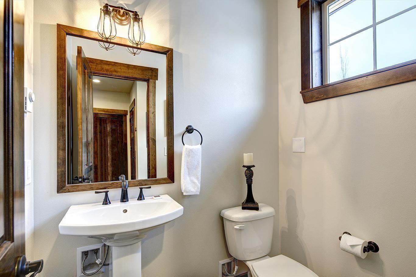 A bathroom with a white sink, a toilet, a large mirror, and a window.
