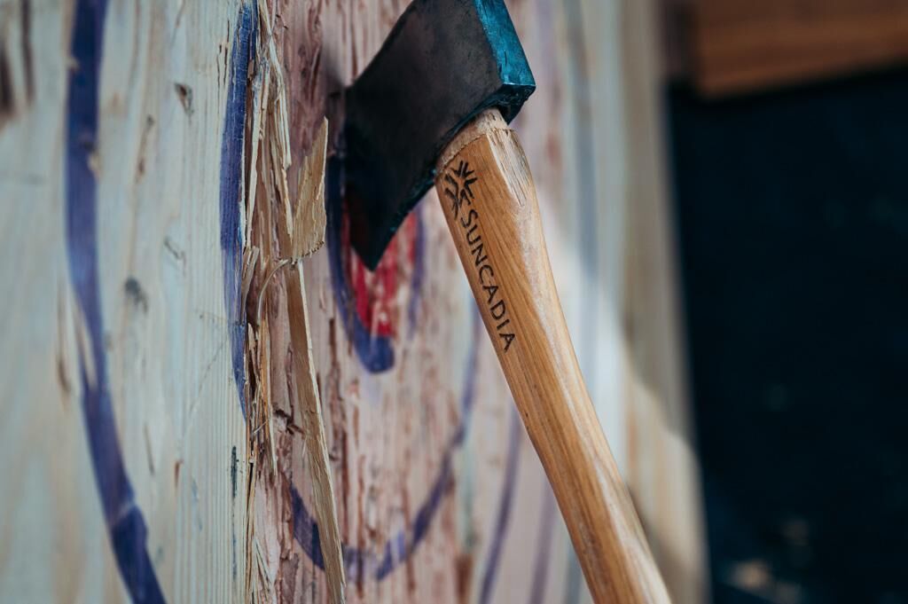A close-up of a wooden-handled axe with the brand name "SUNCADA" engraved on it.