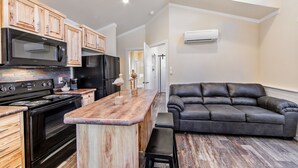 A modern kitchen with wooden cabinets, a black stove, and a marble countertop. - Southern Breeze Lodge (Golden Meadow)
