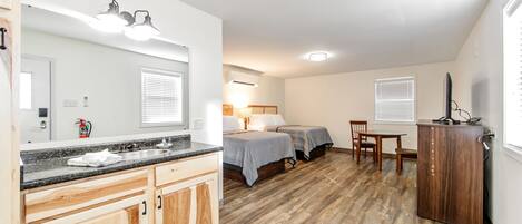 Ein kompaktes Zimmer mit Küchenzeile, einem Bett und einem kleinen Esstisch.