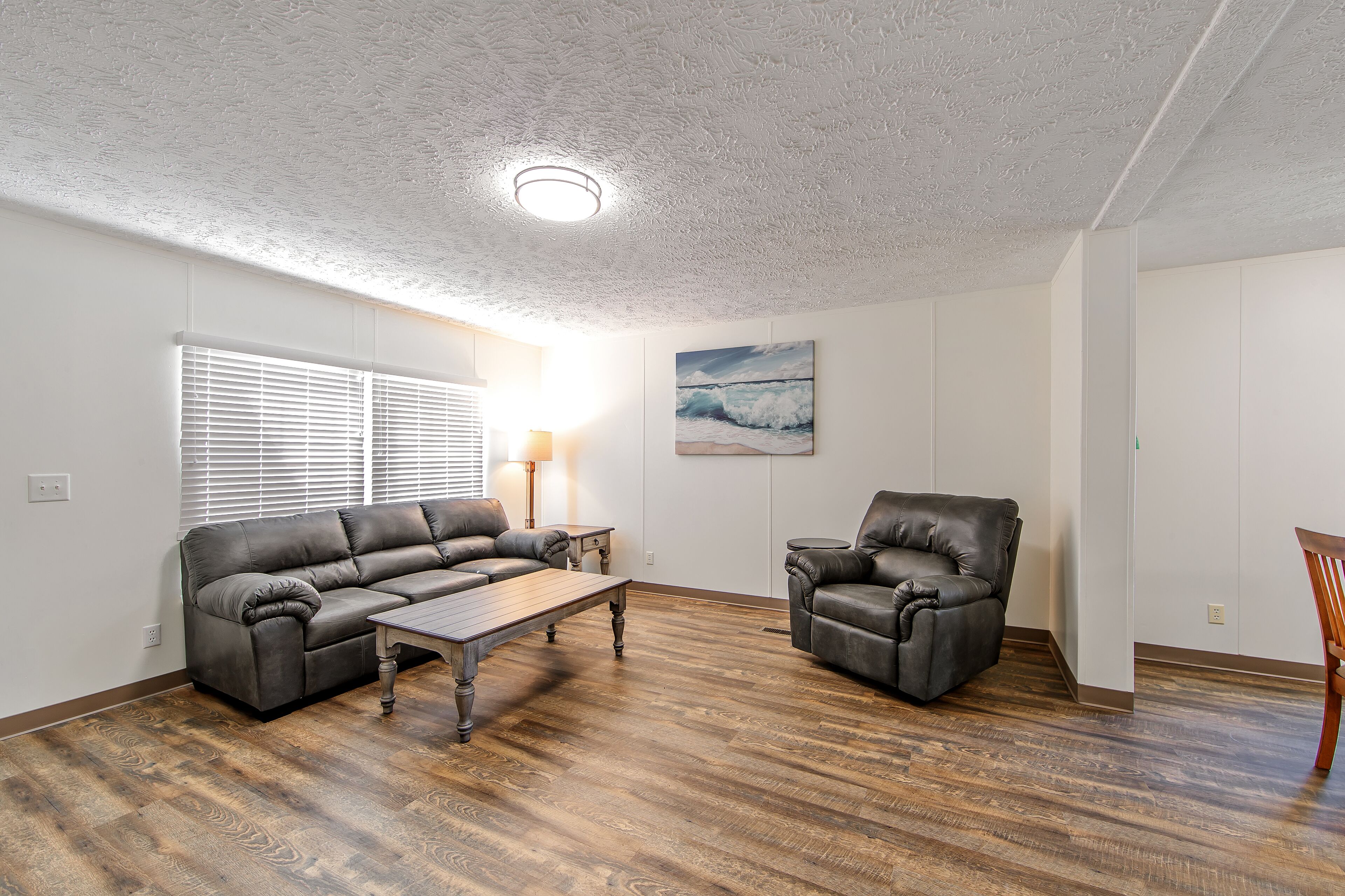 A living room with a sectional sofa, a leather armchair, and a wooden coffee table.