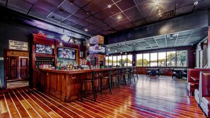 A bar area with wooden flooring, bar stools, and a Coors Light sign. - Southern Breeze Lodge (Golden Meadow)
