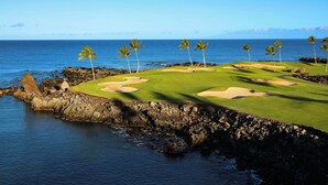 En golfbana vid kusten med fri utsikt över havet och en klippig strandlinje.