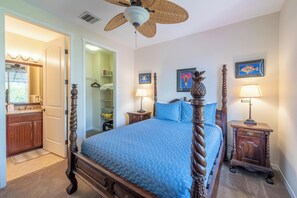 Une chambre à coucher avec un lit à baldaquin, un ventilateur de plafond et deux tables de chevet avec des lampes.