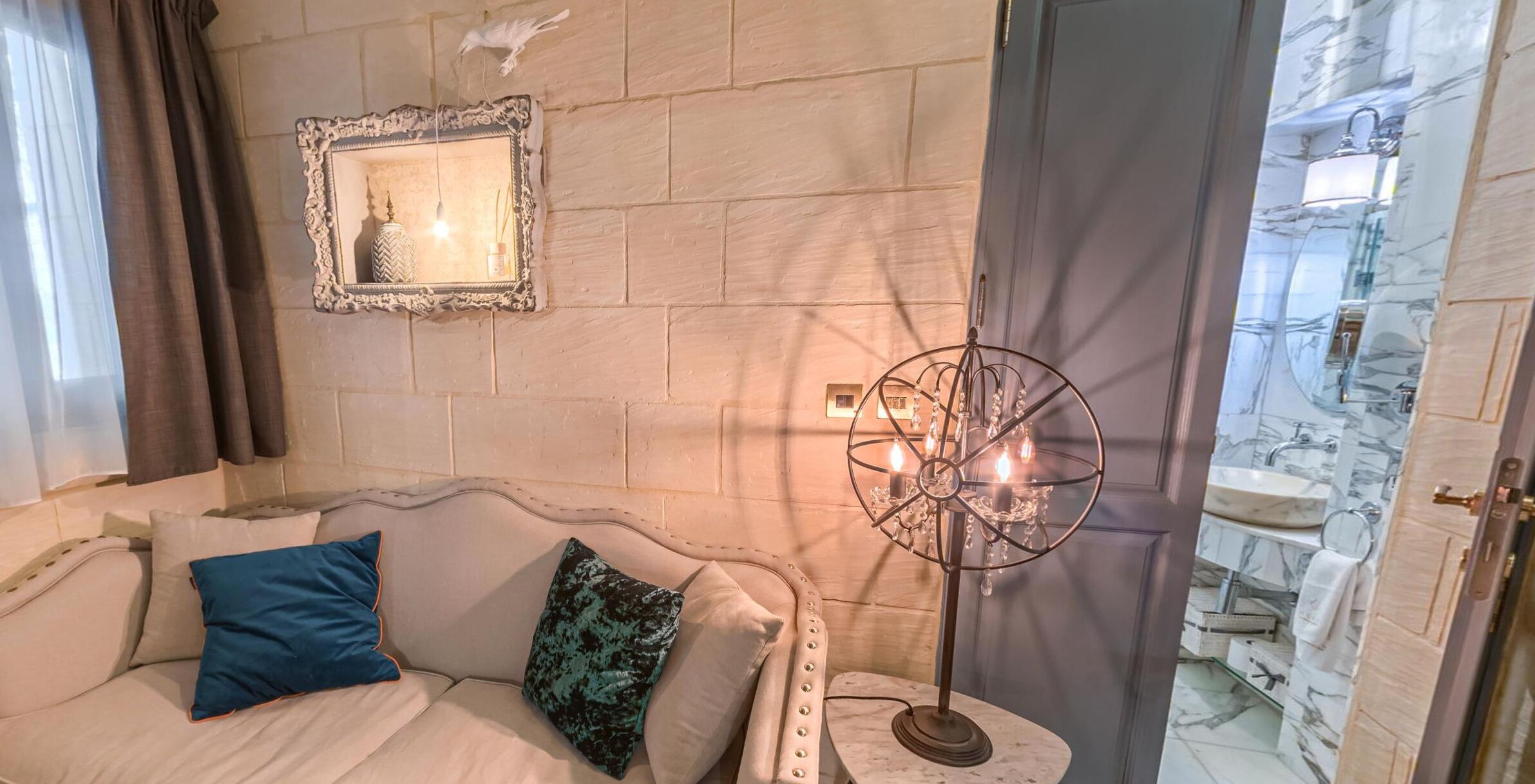 A room with a white sofa, a decorative mirror, and a floor lamp.