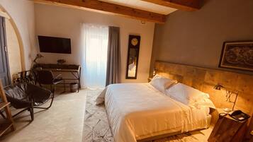 Een hotelkamer met een bed, bureau, stoel en een klok aan de muur.