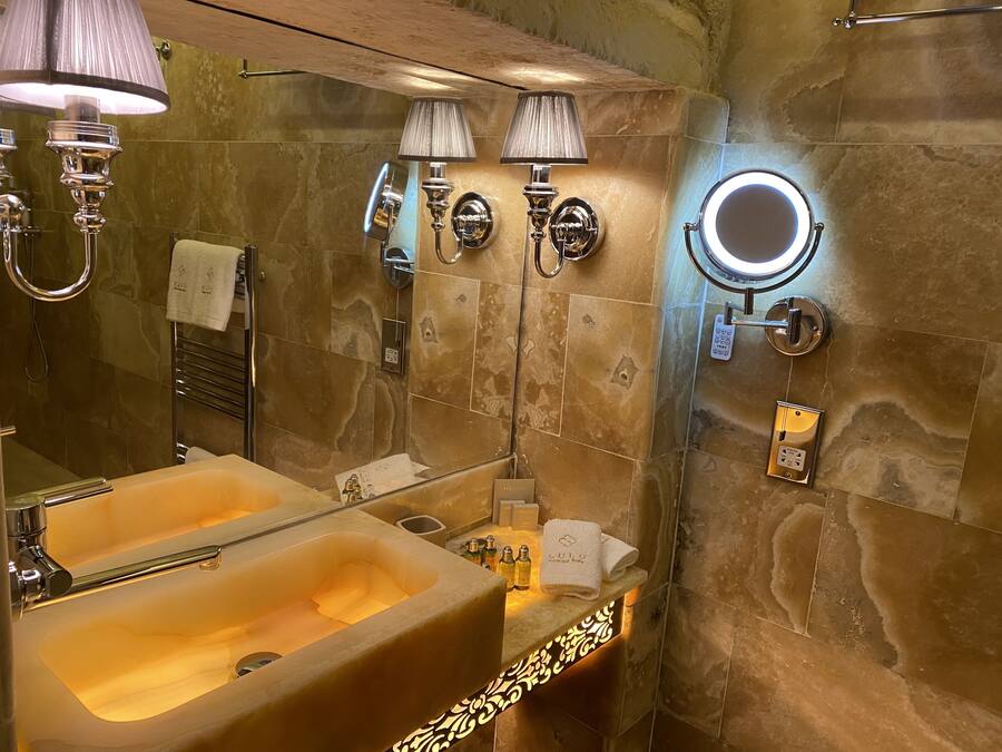 Baño con lavamanos doble, espejo de tocador, toallero e iluminación en la pared.