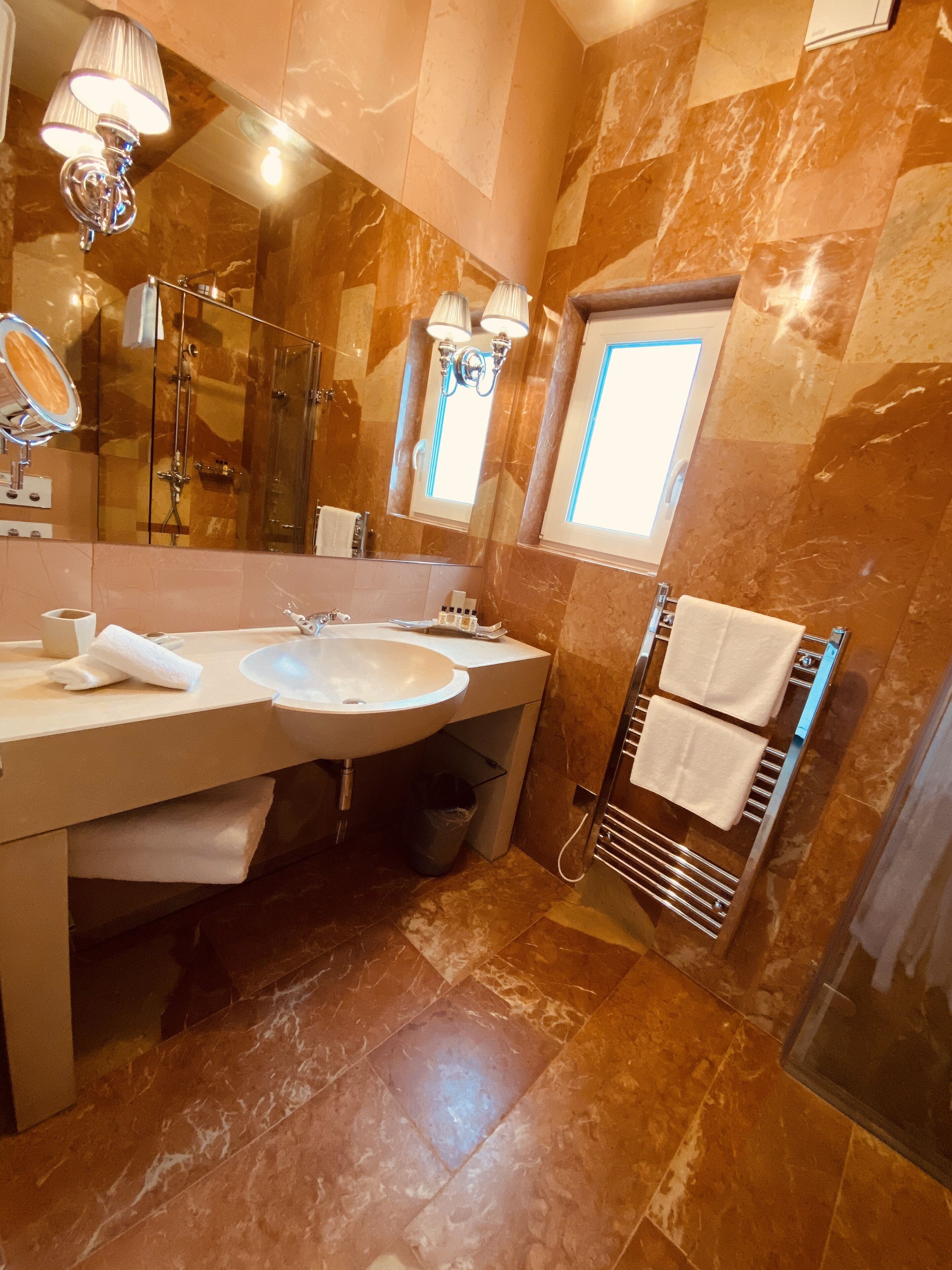 A modern bathroom with a large sink, mirror, and towel rack.