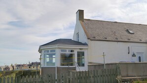 A coastal building with a white exterior, a grey roof, and a small window. - Seabreezes - UK30690 (Portknockie)