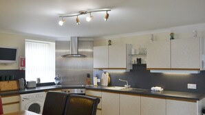 A modern kitchen with a dining area, stainless steel appliances, and a flat-screen TV. - Seabreezes - UK30690 (Portknockie)