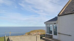 A coastal house with a view of the sea, a small staircase, and a white exterior wall. - Seabreezes - UK30690 (Portknockie)