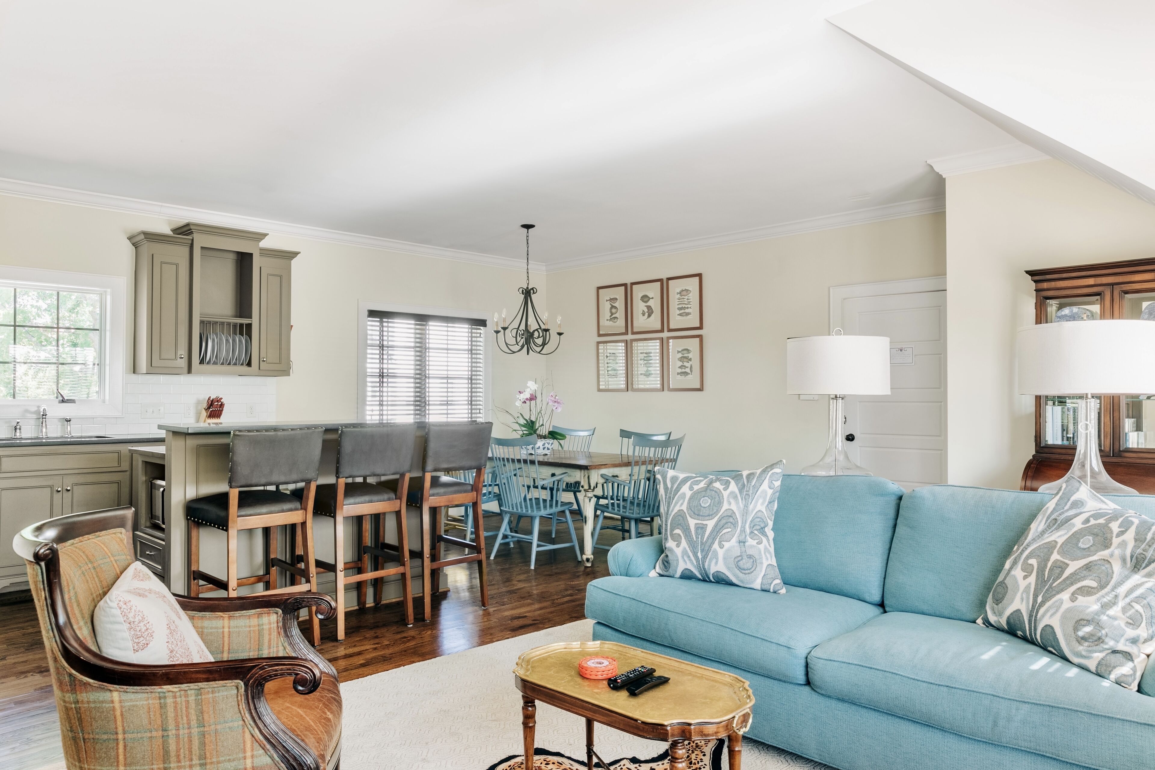 A spacious living room with a blue sofa, a wooden coffee table, and a dining area with a chandelier.