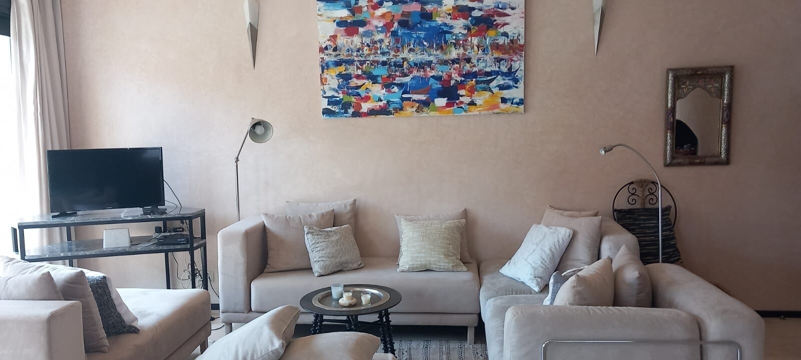 A living room with a sofa, armchairs, a coffee table, a TV, and a painting on the wall.