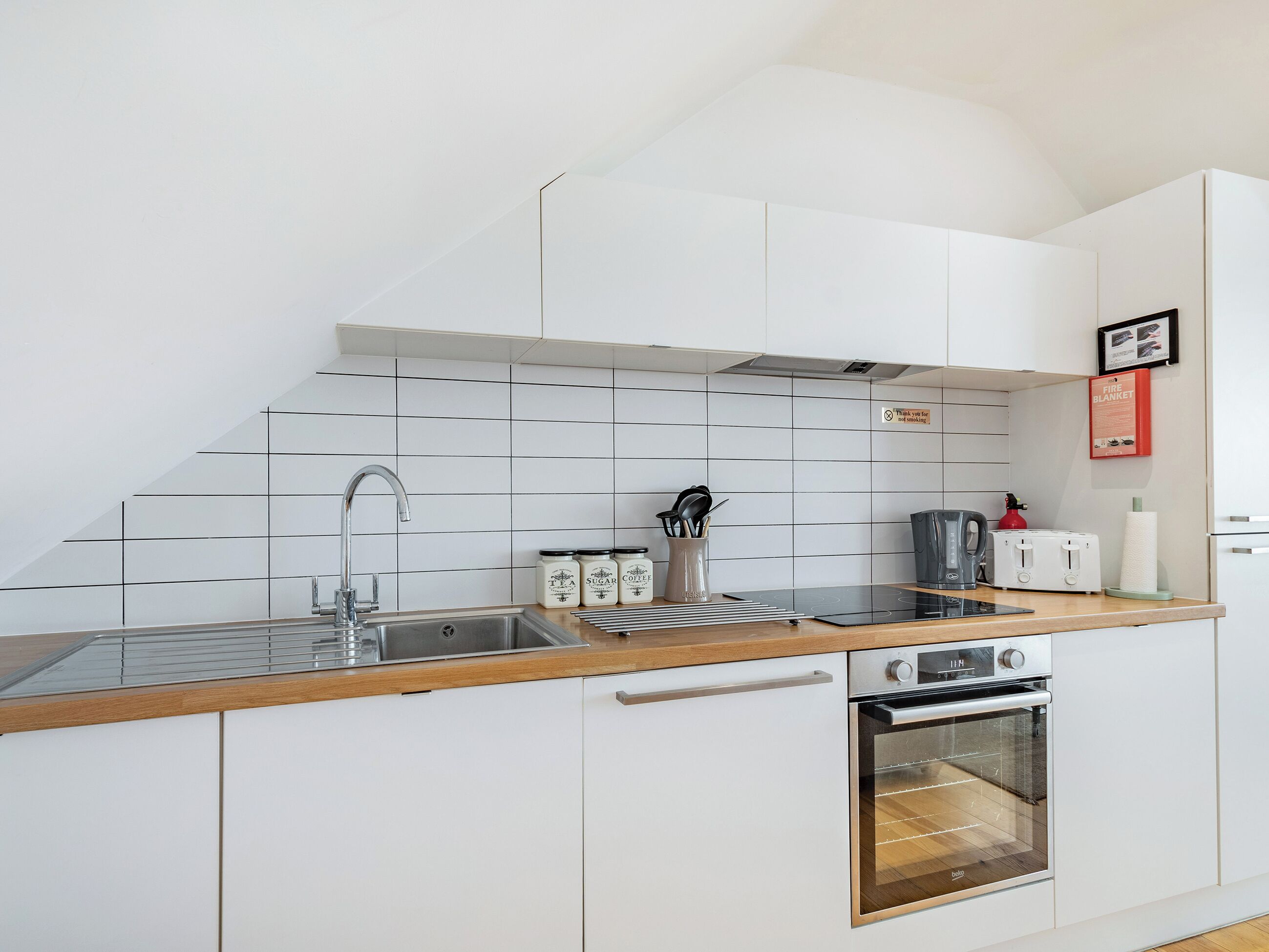 A modern kitchen with white cabinetry, a stainless steel sink, and a built-in oven.