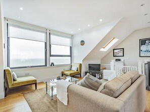 A modern living room with a sofa, armchairs, a glass coffee table, and a television. - 2 bedroom accommodation in Port William (Port William)