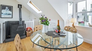 En modern inredning med ett matbord i glas, en öppen spis och utsikt genom ett stort fönster.