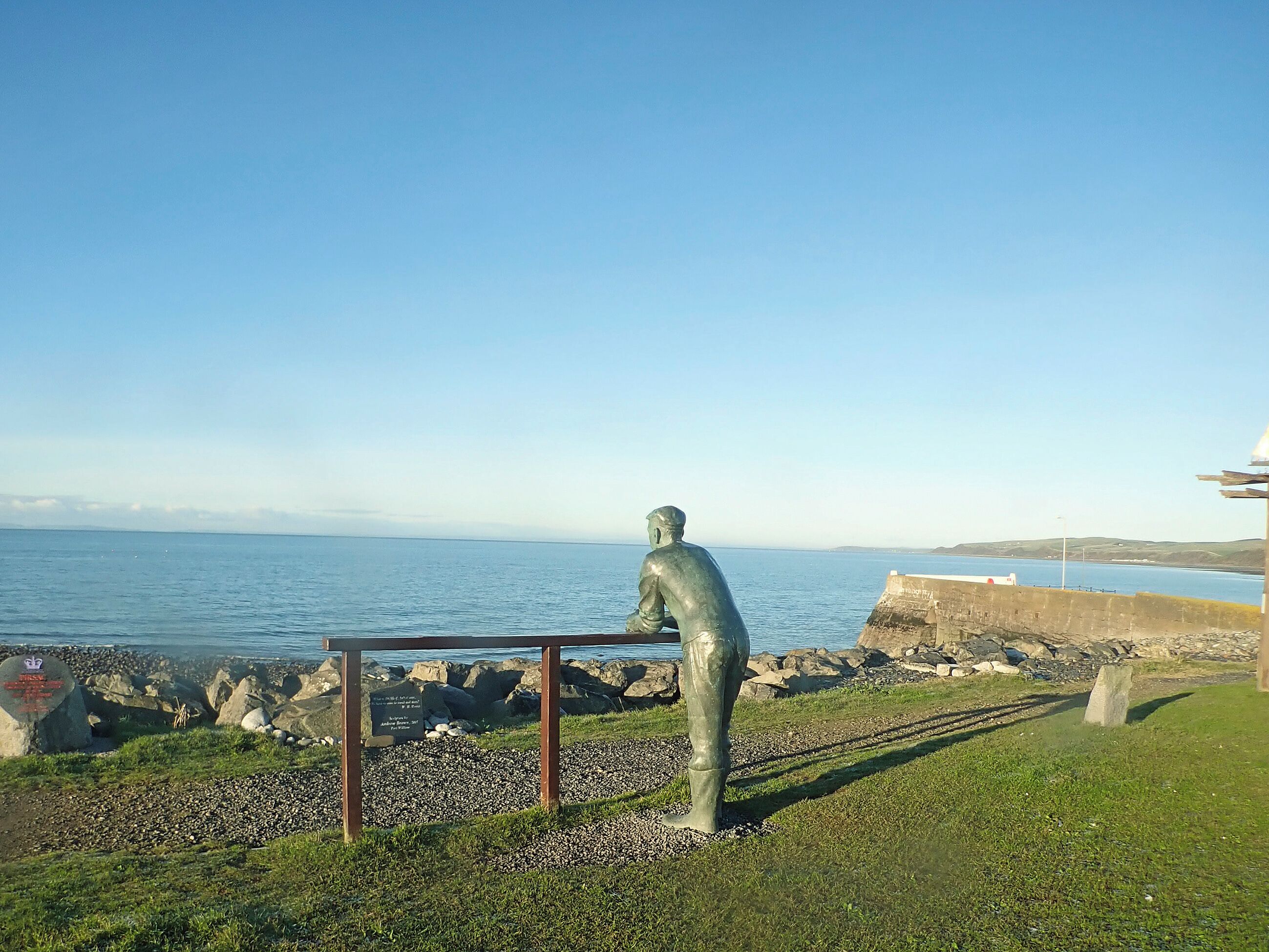 A statue of a man standing by a railing overlooking a body of water.