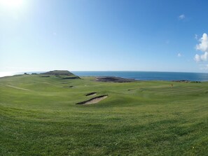 A golf course with a coastal view, bunkers, and a flagstick. - 2 bedroom accommodation in Port William (Port William)