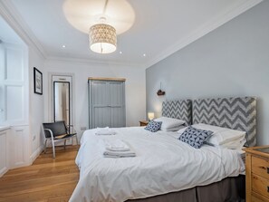 Ein Schlafzimmer mit einem Bett, Nachttischen, einem Kleiderschrank, einem Sessel und einer Pendelleuchte.