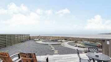 A wooden deck with outdoor seating, a curved pathway, and a view of the sea.