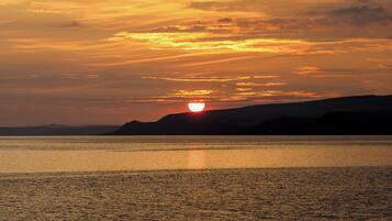 Solnedgang over et roligt vandareal med fjerne landskaber.