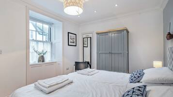 Un dormitorio con cama, armario, ventana y lámpara colgante.