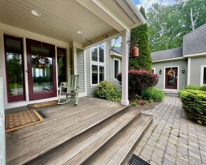 A wooden porch with steps leading to a door, a rocking chair, and a small garden area with a bush and flowers. - Enjoy Every Season at this Serene Estate with Incredible Mountain Views ! (Peru)
