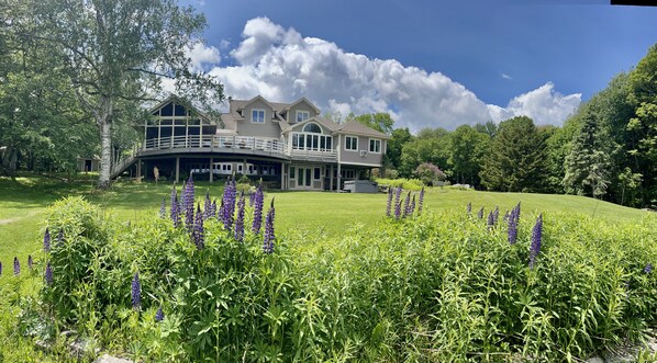 A large, two-story house with a covered porch and a well-maintained lawn with purple flowers. - Enjoy Every Season at this Serene Estate with Incredible Mountain Views ! (Peru)